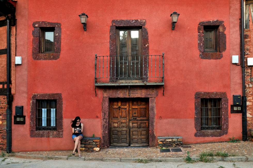 Fachada de color almagre en Alquité, uno de los pueblos amarillos de la sierra de Ayllón, en Segovia. El color azafranado de la mayoría de sus casas y muros proviene de las cuarcitas empleadas en su construcción, como se puede ver en el poyo en el que está sentada la joven de la foto.