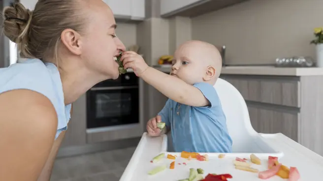 Bebe dandole de comer a una madre.