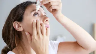 Mujer utiliza colirio en sus ojos.