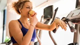 Mujer joven come una manzana después de entrenar.