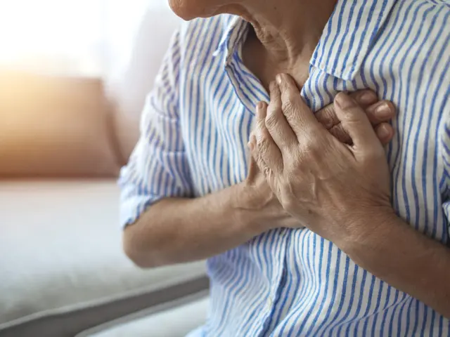 Una mujer madura lleva sus manos al pecho en señal de dolor.