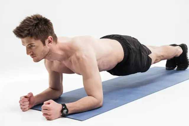 Un hombre practica ejercicio haciendo una plancha.