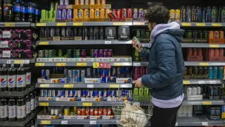 Un joven mira la sección de bebidas energéticas en el supermercado.