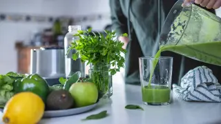 Una mujer preparando un batido verde en su cocina